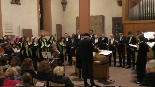 Ein gemischter Chor singt in der evangelischen Kirche in Schönau. Der Dirigent steht dabei neben einem Klavier, die Pianistin und ein Mann mit einem Chello begleiten den Chor.